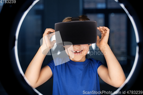 Image of boy in vr glasses over illumination in dark room