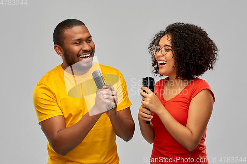 Image of happy african couple singing to hairbrushes