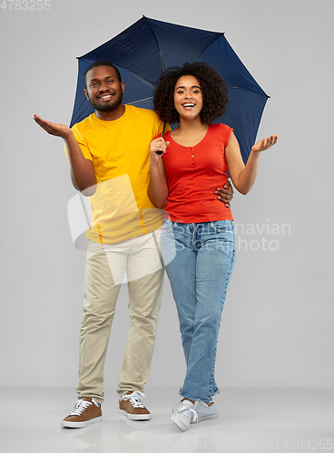 Image of smiling african american couple with umbrella