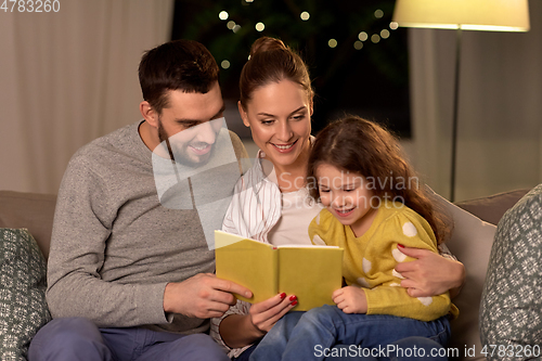 Image of happy family reading book at home at night