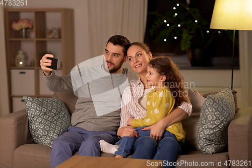 Image of happy family taking selfie at home at night