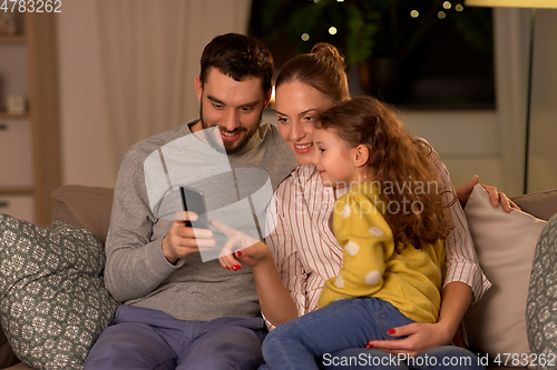Image of happy family with smartphone at home at night