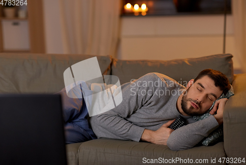 Image of man sleeping on sofa with tv remote at home