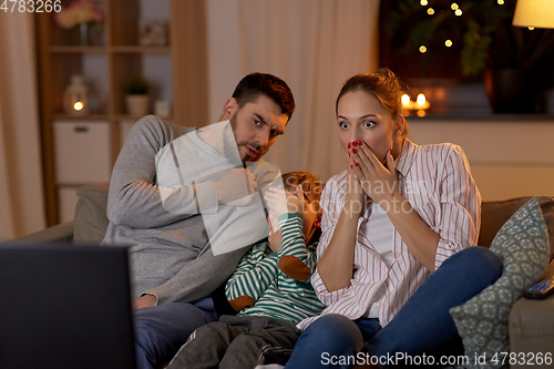 Image of scared family watching tv at home at night