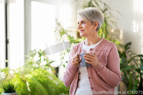 Image of happy senior woman with cup of tea at home