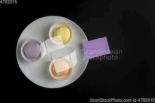 Image of Marshmallows in cups on white plate on black background