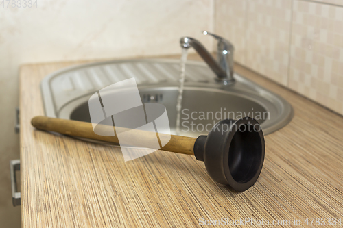 Image of Household plumbing tool for clearing blockages is a plunger at the kitchen sink