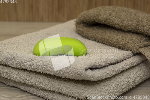 Image of Body wash and a bar of green soap on a terry towel in bath