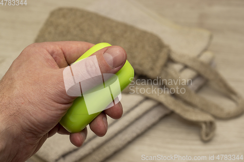 Image of A piece of soap in hand on background of a terry towel and washcloth