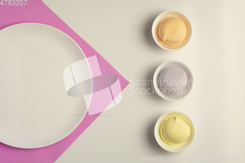 Image of Multicolored marshmallows in white cups and empty white dish on pink