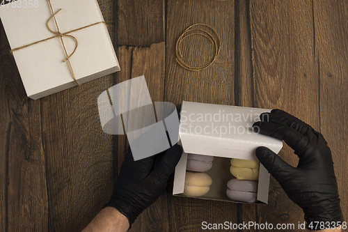 Image of Hands in black gloves pack marshmallows in box in food delivery service