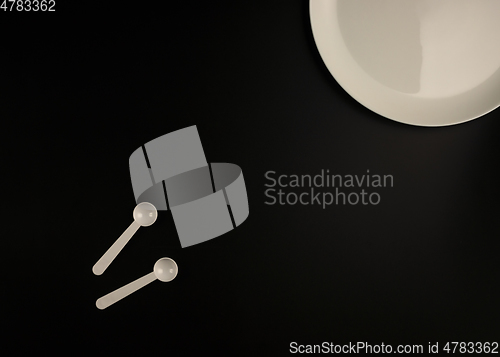 Image of White plate and white spoons on black background