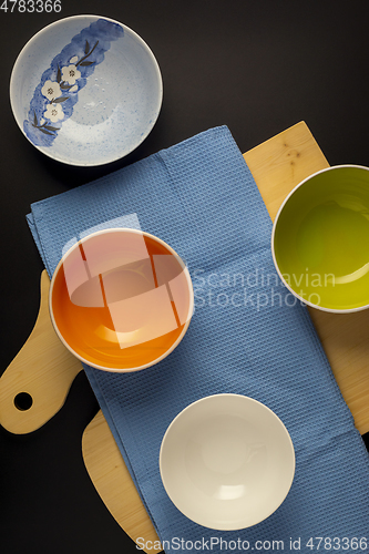 Image of Empty bowls on waffle towel and cutting board on black background