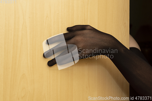 Image of Hand in black sexy nylon glove on door of room entices into a sweet trap