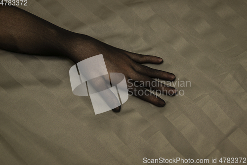 Image of Graceful female hand in seductive nylon glove on bedsheet