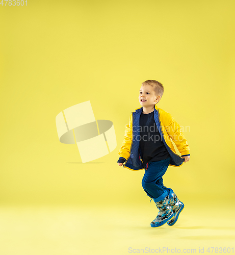 Image of A full length portrait of a bright fashionable boy in a raincoat