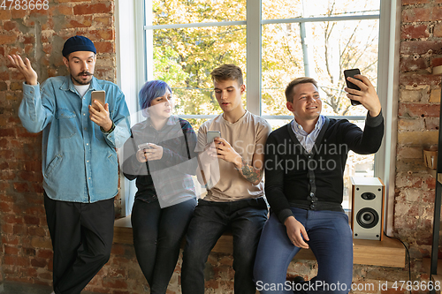 Image of Group of happy young men and women sharing in social media