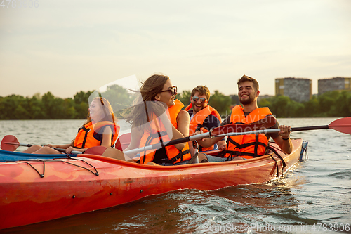 Image of Happy friends kayaking on river with sunset on the background