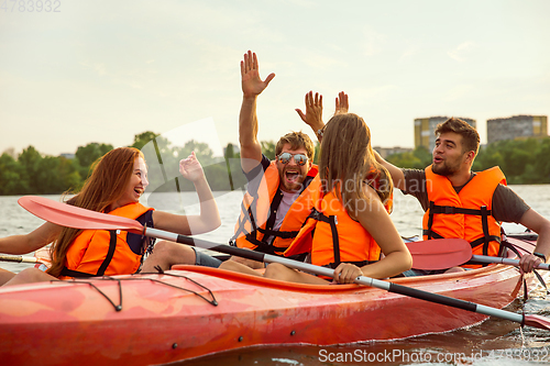 Image of Happy friends kayaking on river with sunset on the background