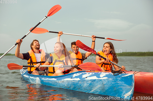 Image of Happy friends kayaking on river with sunset on the background