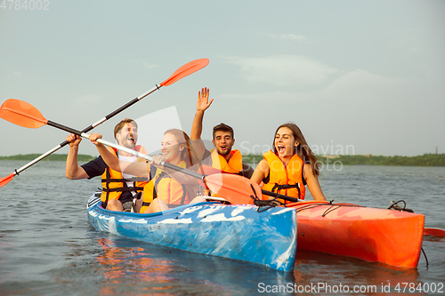 Image of Happy friends kayaking on river with sunset on the background