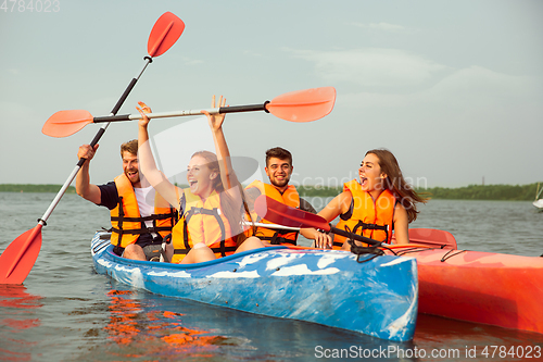 Image of Happy friends kayaking on river with sunset on the background