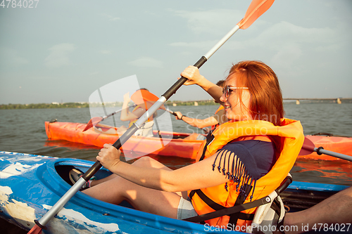 Image of Caucasian woman kayaking on river with sunset on the background