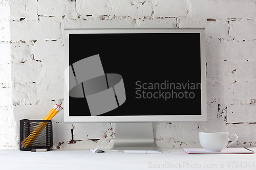 Image of Mock up empty black monitor screen on white brick wall background