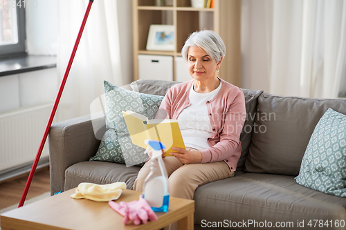 Image of senior woman reading book after home cleaning