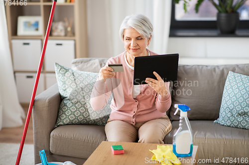 Image of old woman with tablet pc and credit card at home