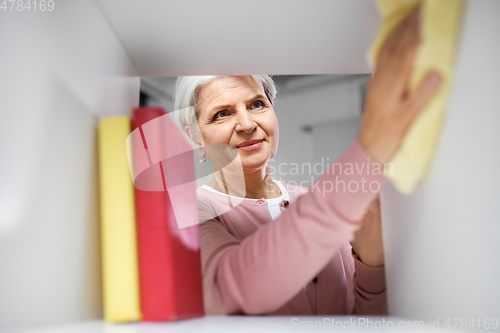 Image of happy senior woman with cloth dusting rack at home