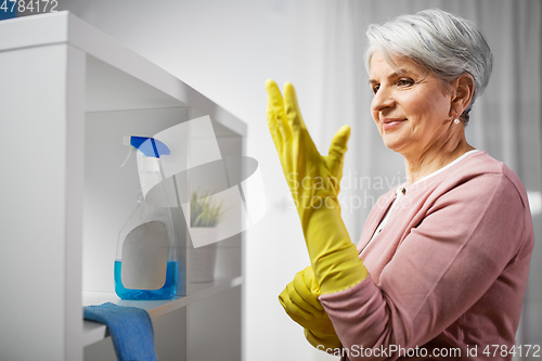 Image of senior woman putting protective rubber gloves on