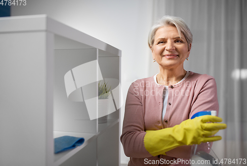 Image of senior woman cleaning rack with detergent at home