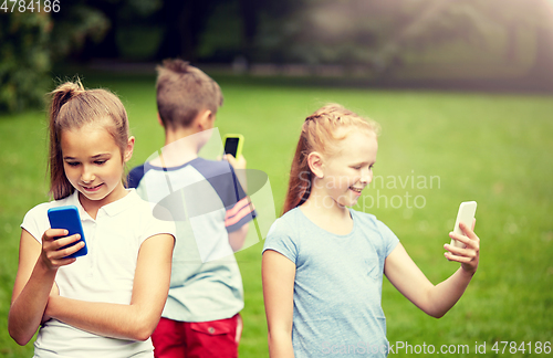 Image of kids with smartphones playing game in summer park