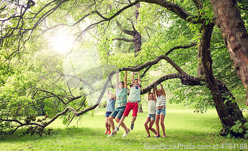 Image of happy kids hanging on tree in summer park