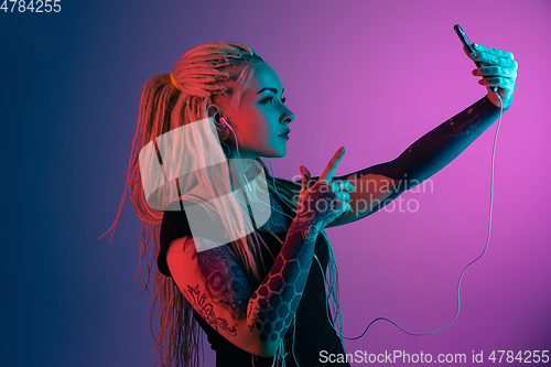 Image of Caucasian young woman\'s portrait on gradient background in neon light