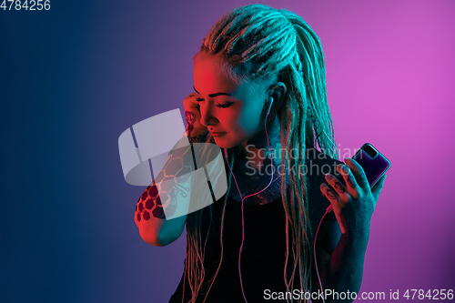 Image of Caucasian young woman\'s portrait on gradient background in neon light
