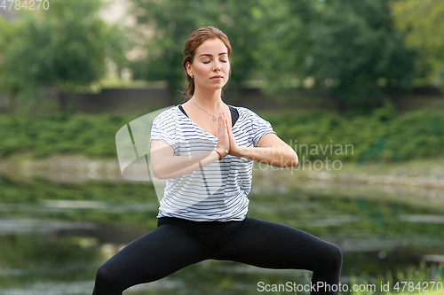 Image of Young beautiful woman doing yoga exercise in green park. Healthy lifestyle and fitness concept.