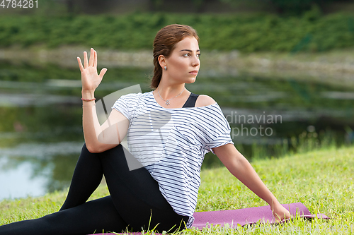 Image of Young beautiful woman doing yoga exercise in green park. Healthy lifestyle and fitness concept.