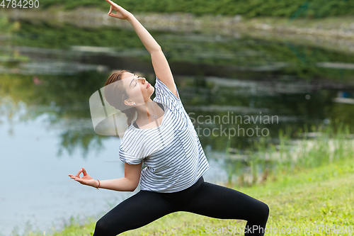 Image of Young beautiful woman doing yoga exercise in green park. Healthy lifestyle and fitness concept.