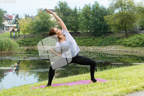 Image of Young beautiful woman doing yoga exercise in green park. Healthy lifestyle and fitness concept.