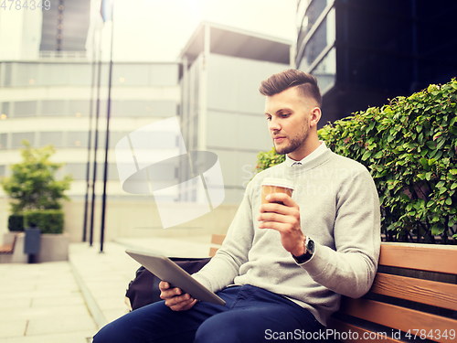 Image of man with tablet pc and coffee on city street bench