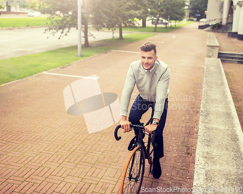 Image of young man riding bicycle on city street