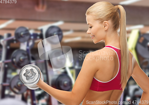 Image of happy young woman with dumbbell exercising in gym