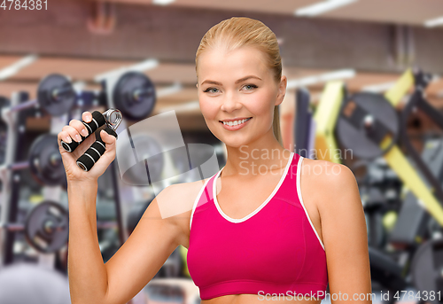Image of smiling woman with hand expander exercising in gym