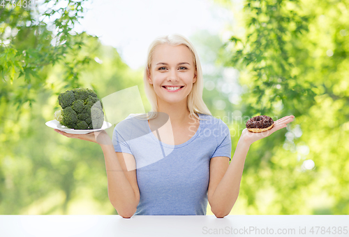 Image of smiling woman choosing between broccoli and donut