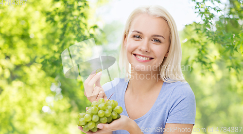 Image of happy woman eating grapes