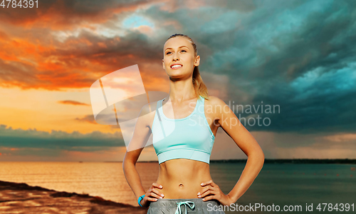 Image of happy young woman exercising over sea