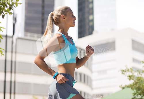 Image of smiling young woman running at city