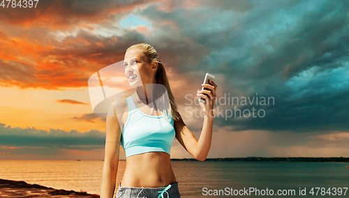 Image of happy woman with smartphone exercising over sea
